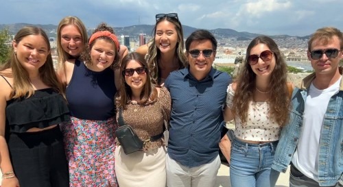 Study abroad students and leaders pose for a group photo with a city and mountains in the background