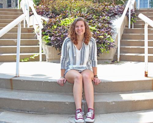 Emma Busch sits on steps on campus