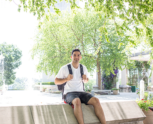 Cesar Aldana sits near the fountains on Rockhurst's campus