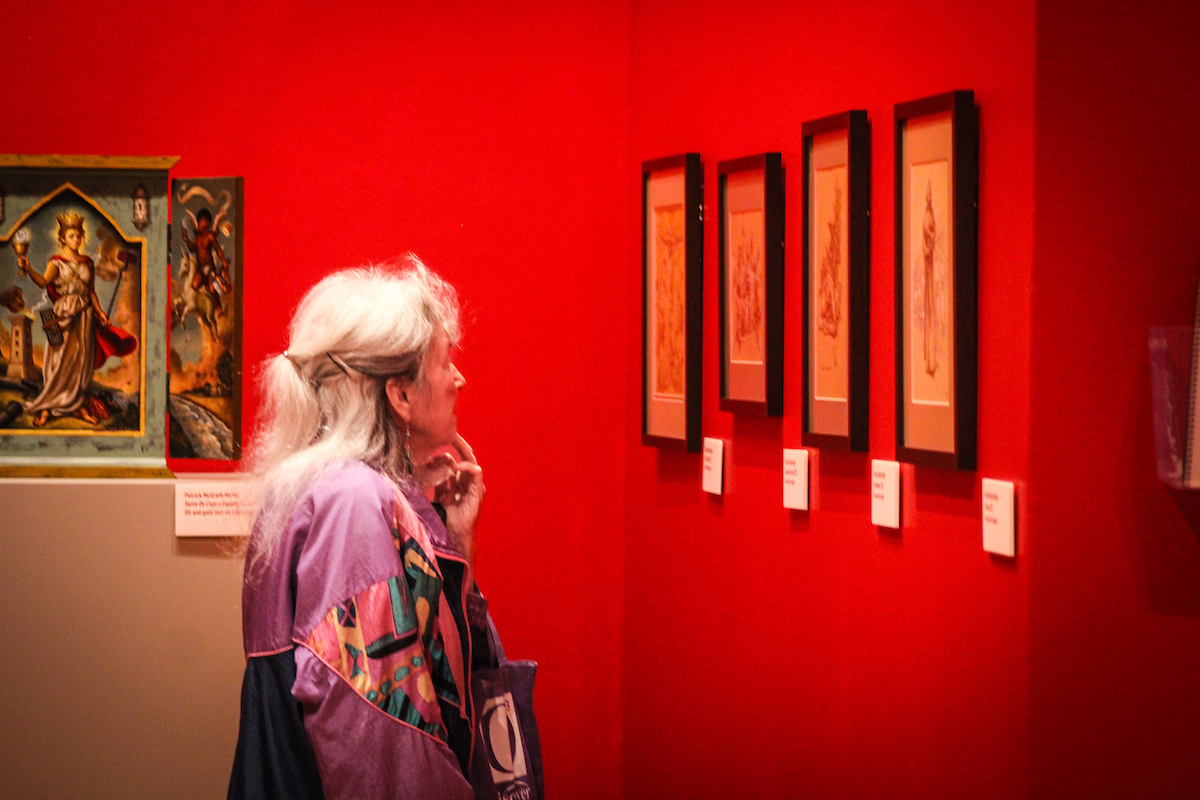 A woman examines paintings on a wall