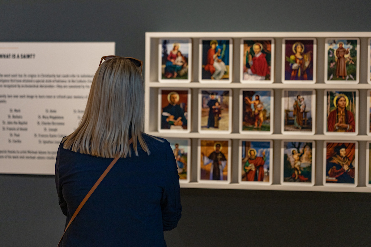 Woman looks at a series of small paintings on shelves