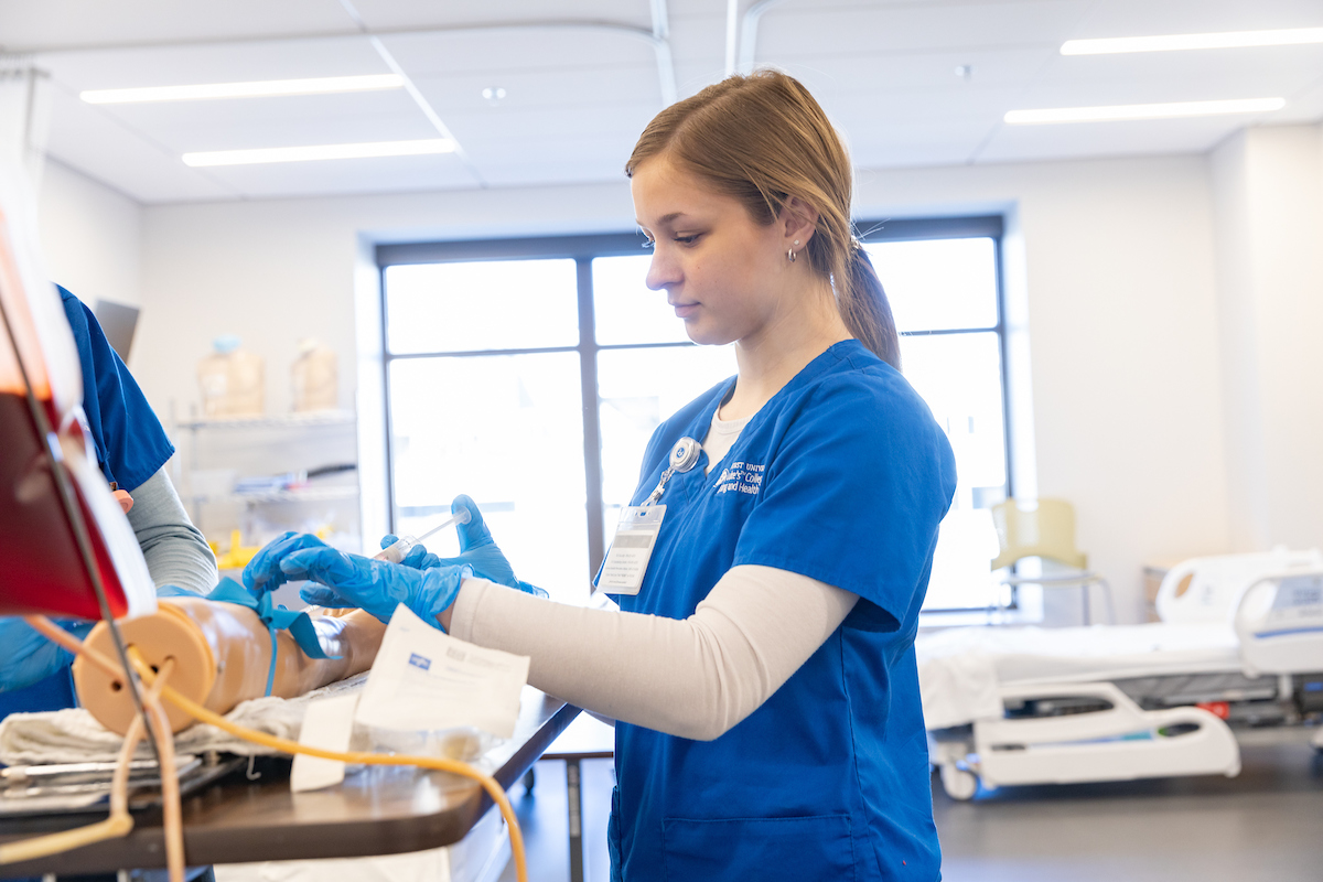 Student practicing using a needle in nursing classroom