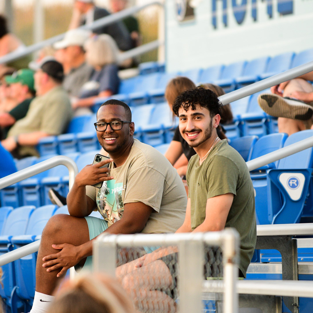 Two male students sitting in the bleachers at Bourke Field