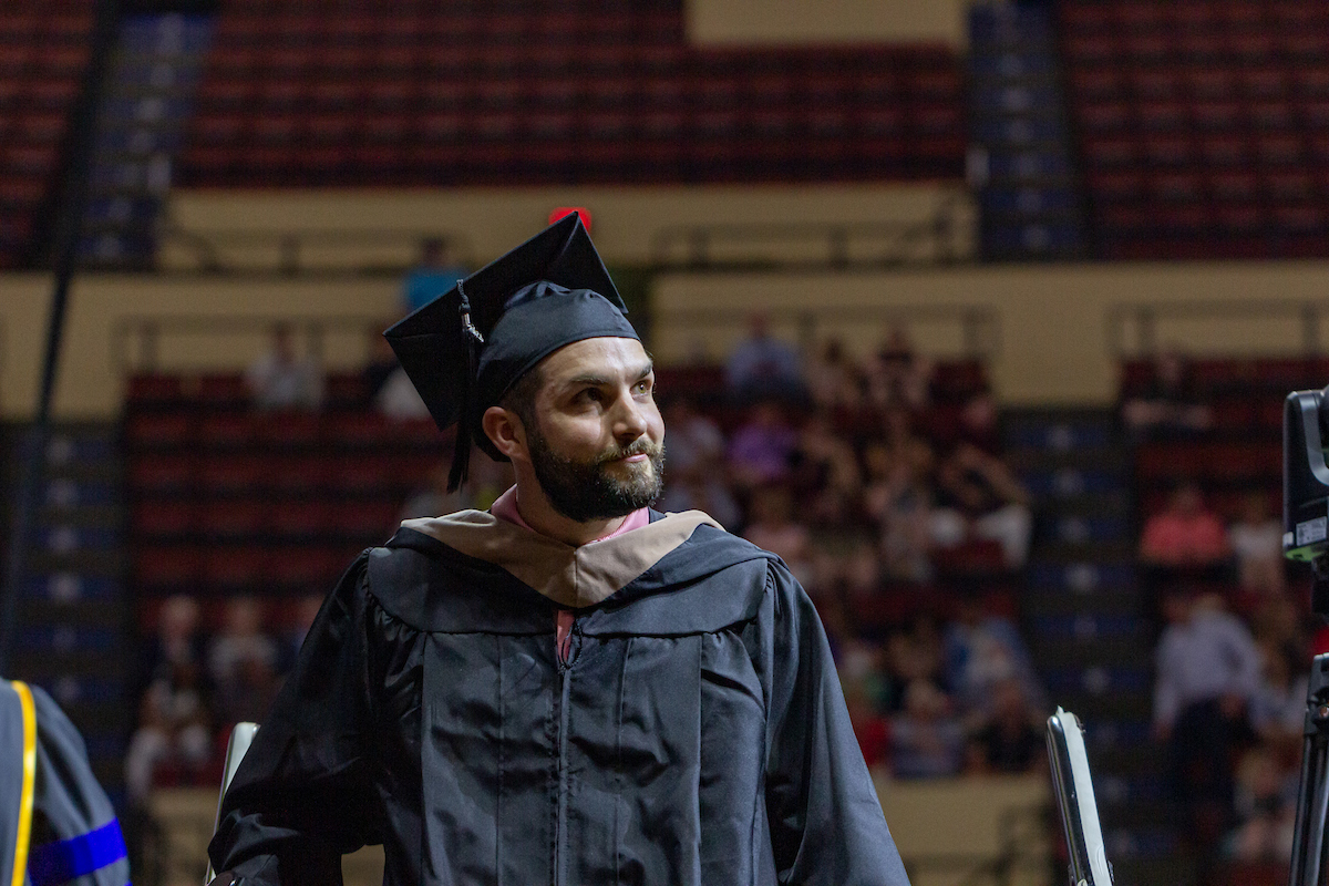 A male graduate looks at the crowd after receiving his diploma