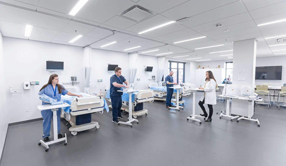 Health students work with an instructor on a simulation hospital floor