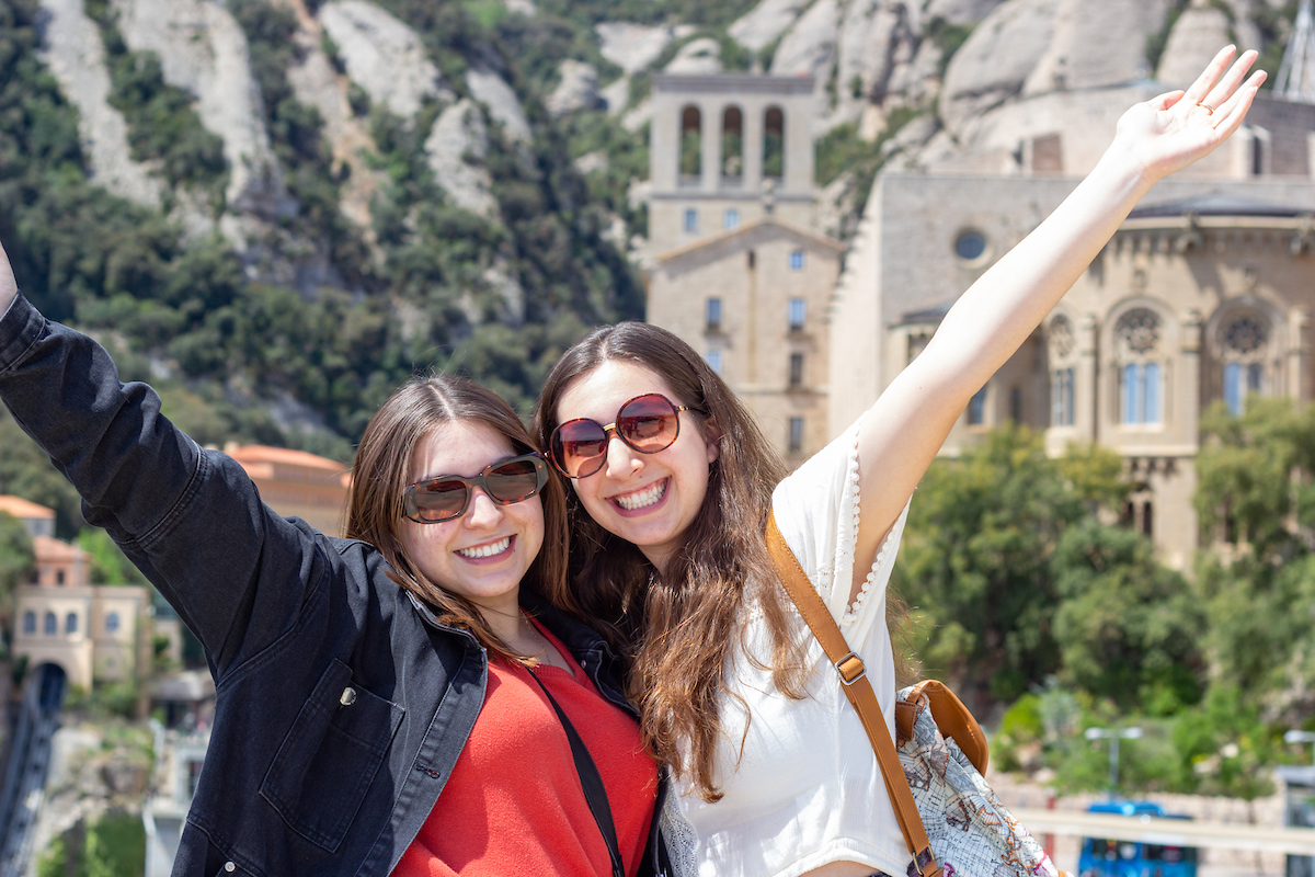 Two friends pose in front of a historic site in Spain