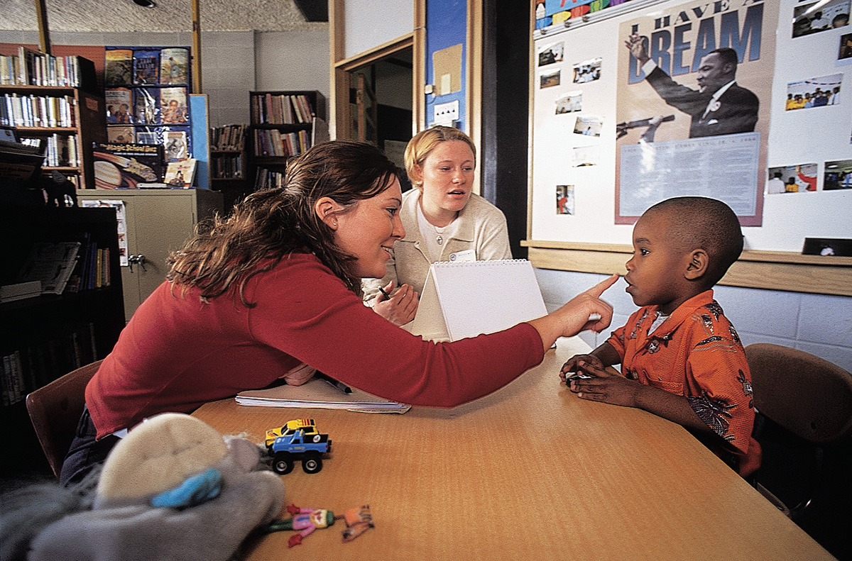 A female SLP student touches the mouth of a child client