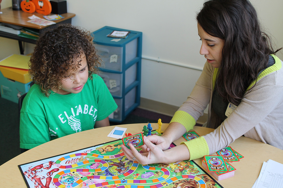 A female SLP student plays Candyland with a child client