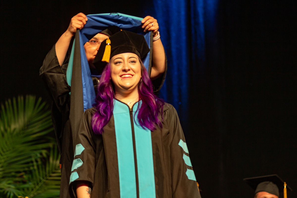 A School of Education graduate gets hooded at Commencement