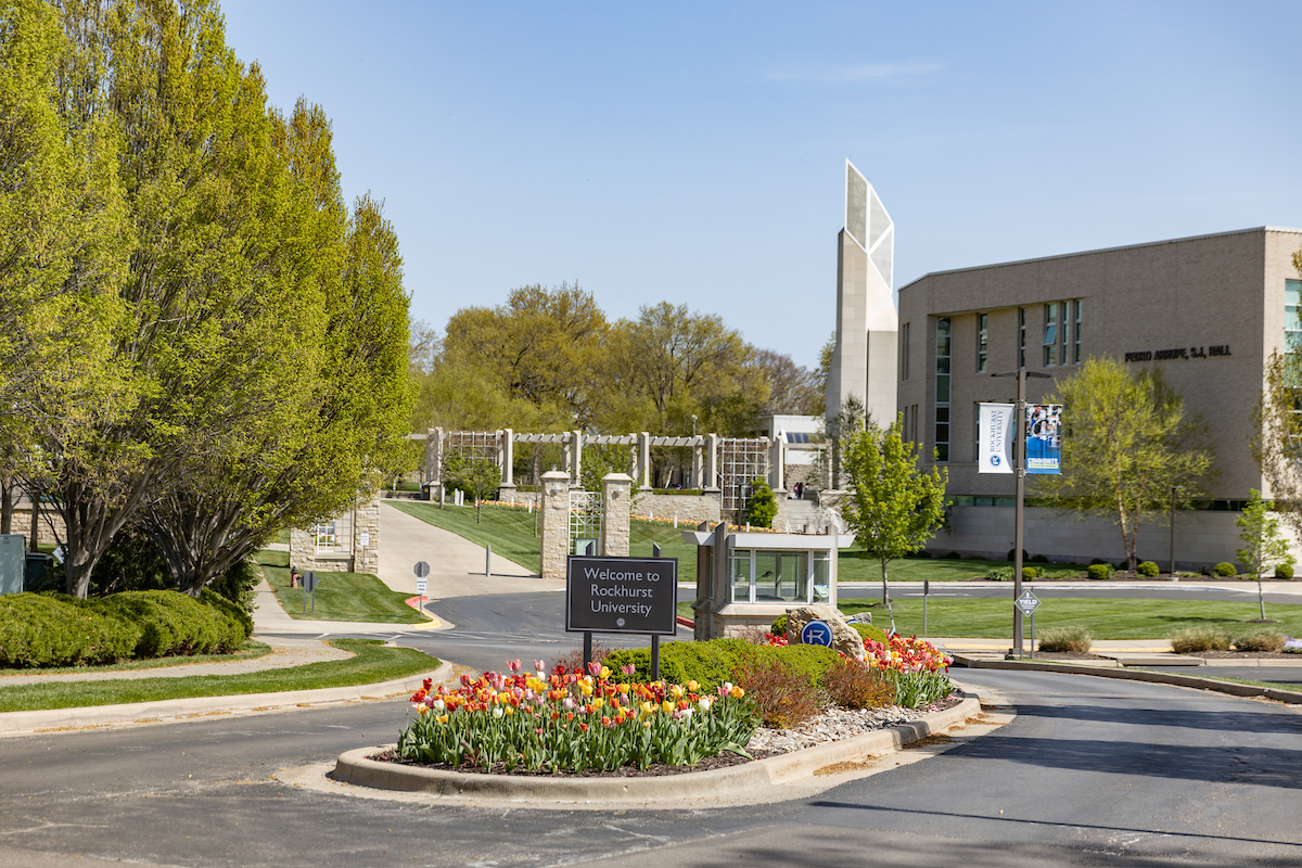 Rockhurst University south entrance with tulips in foreground and Arrupe Hall and bell tower in background