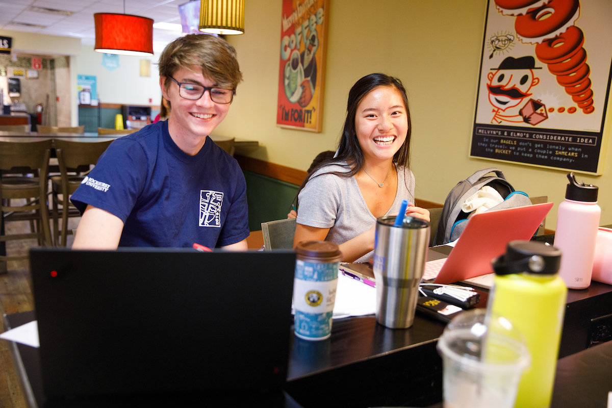 Two students laugh while hanging out at Einstein's Bagels on Rockhurst's campus