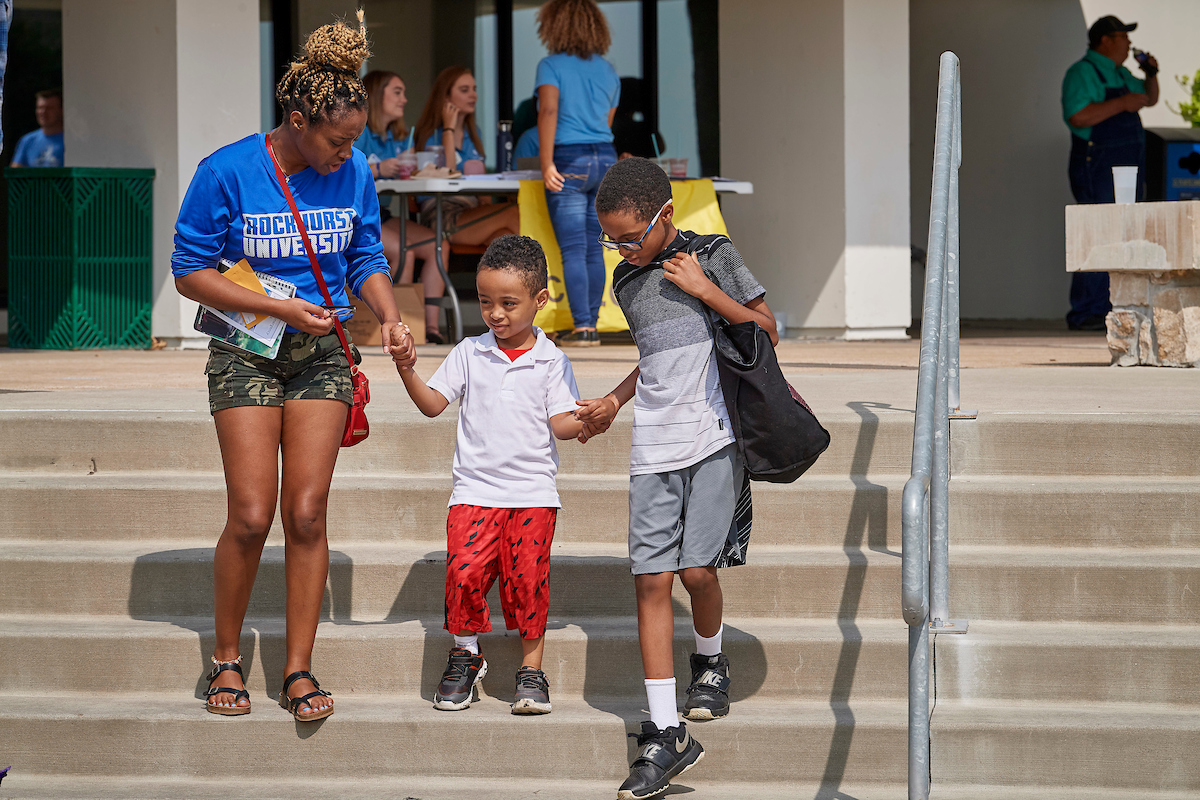 A student leads two kids down the stairs holding hands