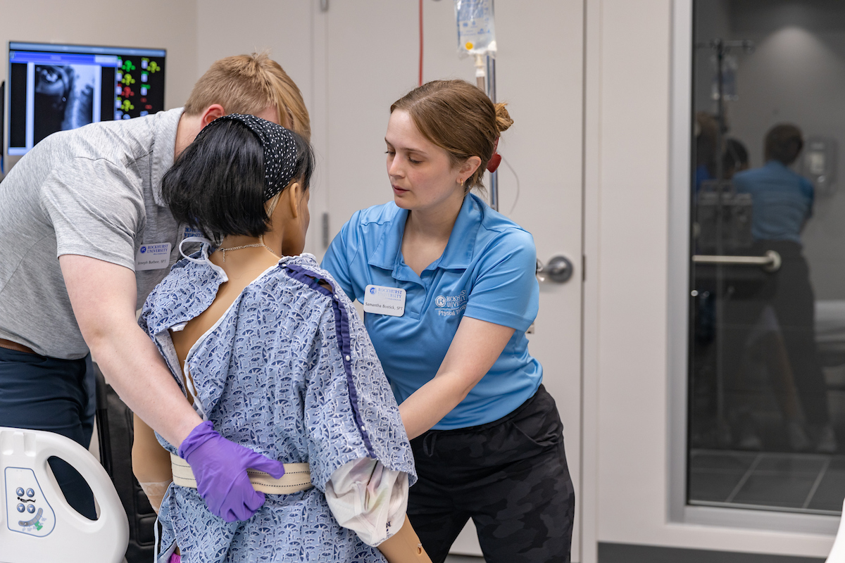 PT students maneuver a mannikin in a simulated hospital room