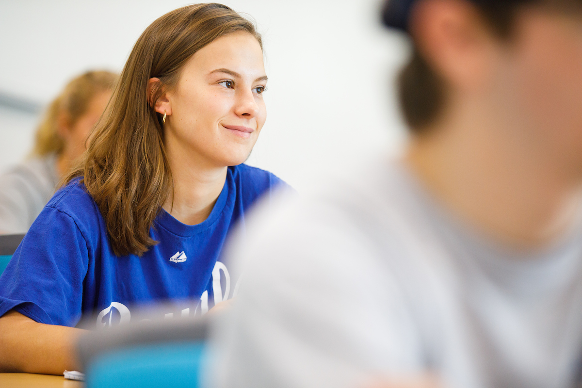 A student in a blue Royals shirt looks forward and smiles