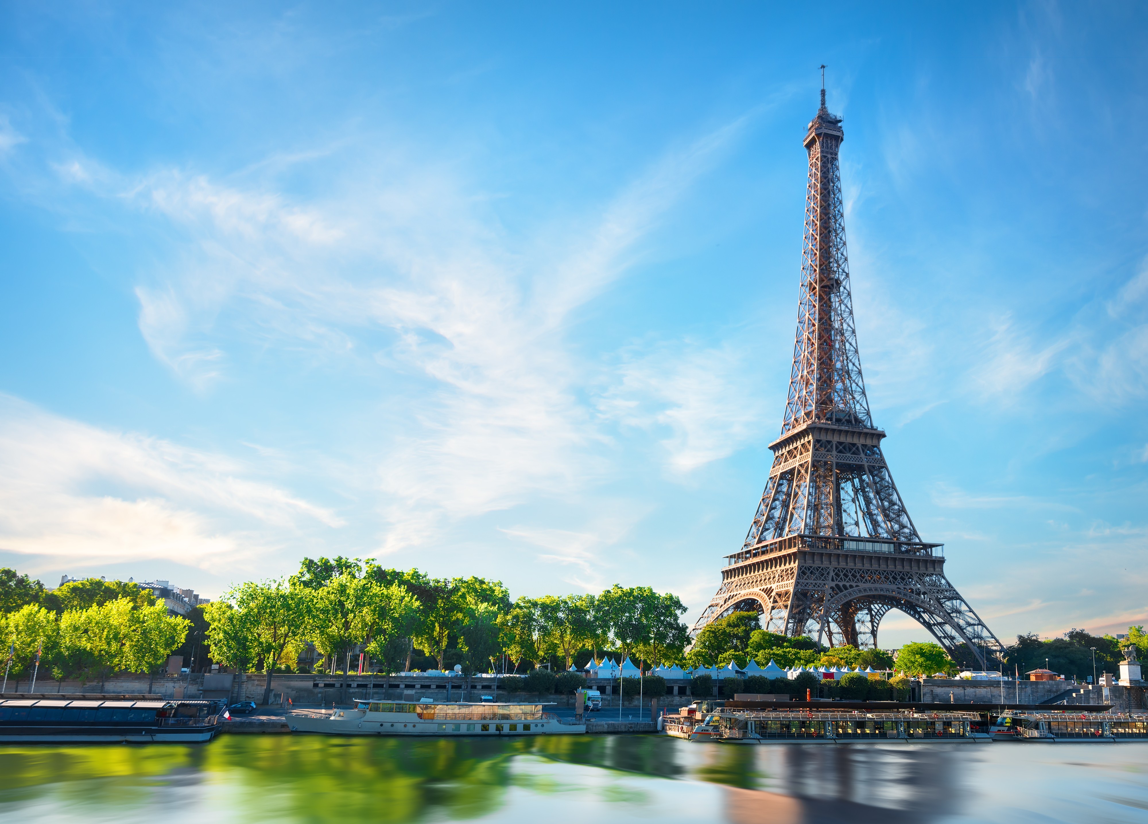 Eiffel tower next to the Siene in Paris, France. Blue sky in the background. 