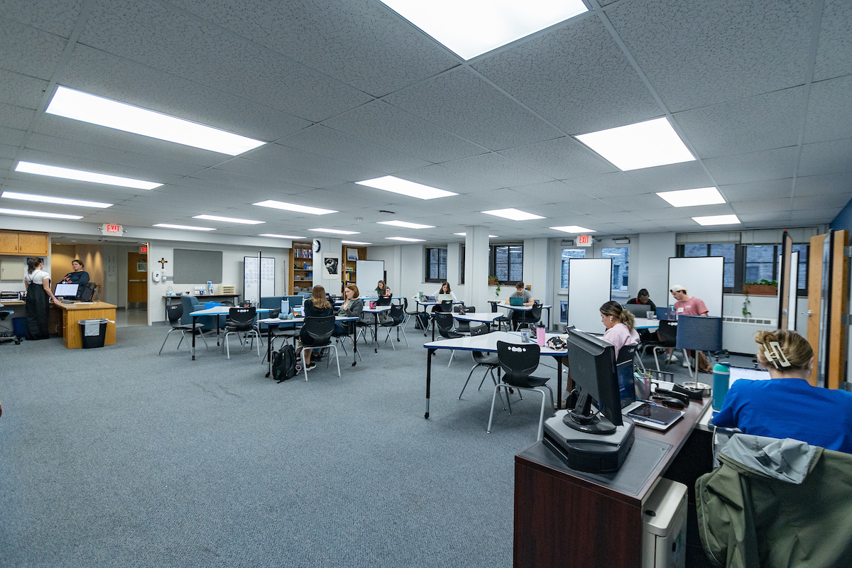 View of the Learning Center from the door, seeing several tables and students studying