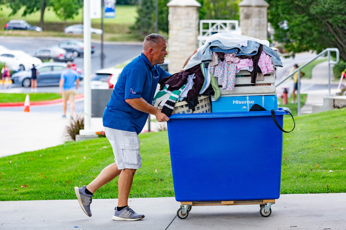 A dad pushes a cart full of his daughter's belongings on move-in day