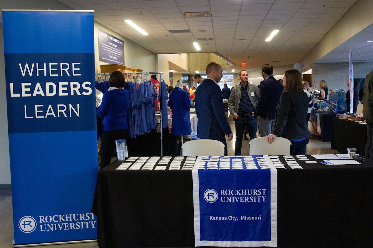 Where Leaders Learn sign next to table with nametags and people mingling. 