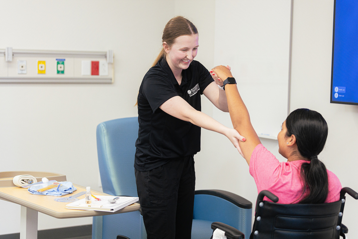 An occupational therapy student helps a girl in a wheelchair