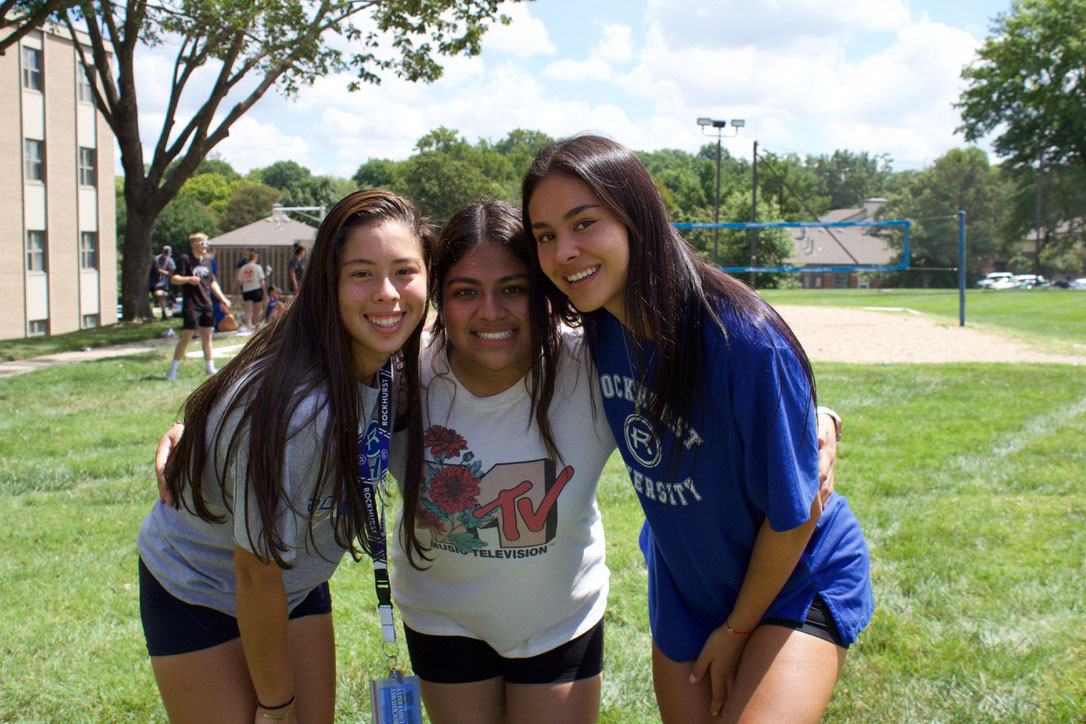 Three friends pose with their arms around each other