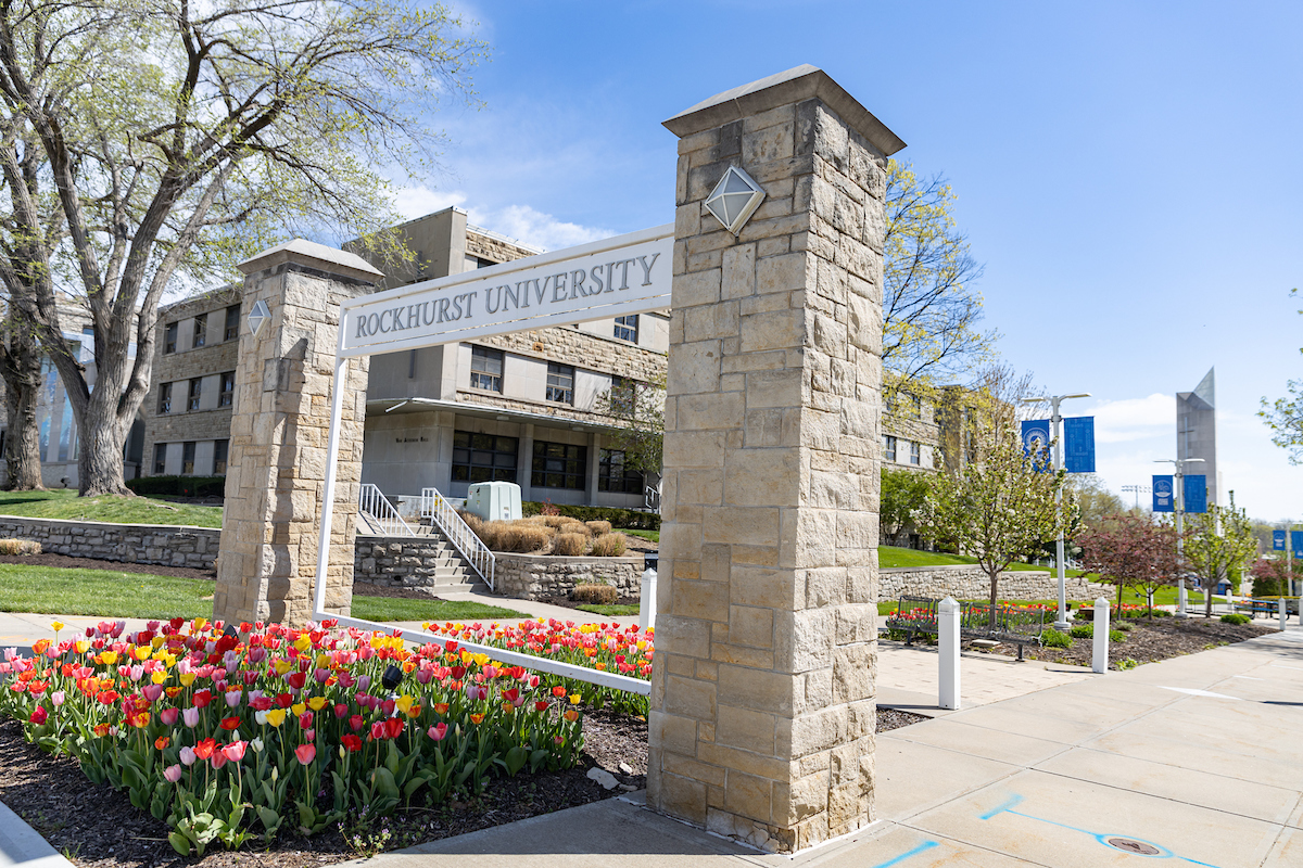 The Rockhurst University gate with the bell tower in the background; tulips in foreground