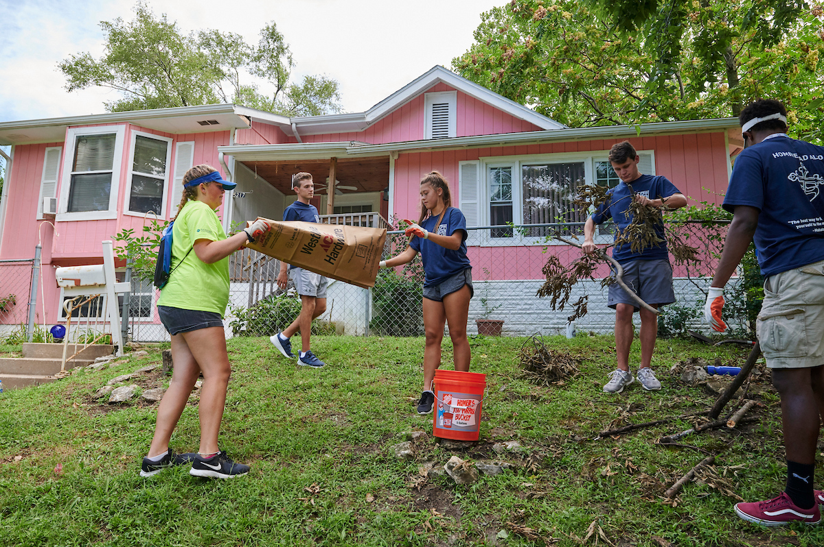 Students clean up the yard of a pink house