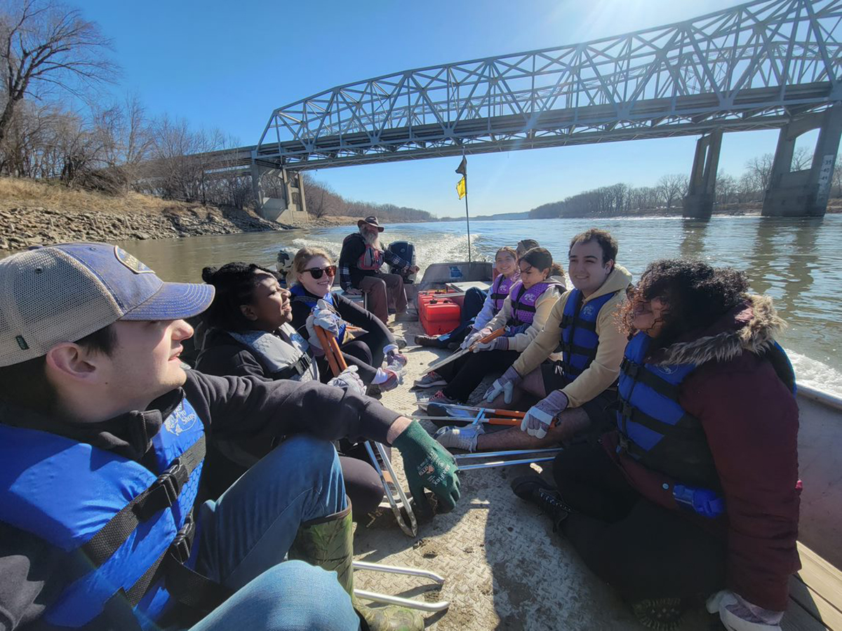 A boat carrying students on a river approaches a large bridge