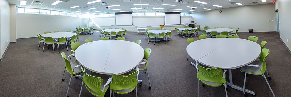 Arrupe 114 classroom with round tables and marker boards