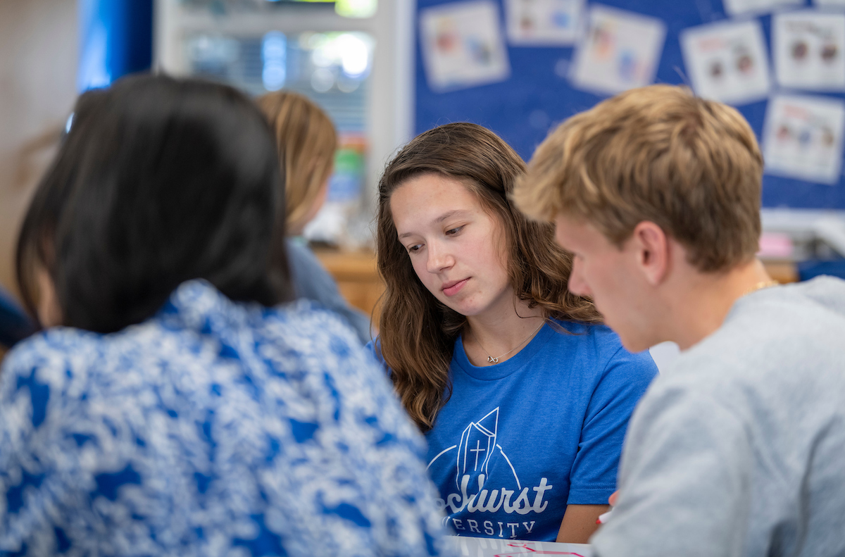 Students in the Learning Center look at an item on the table 