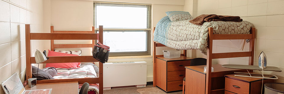 A dorm room with beds on opposite sides of the room