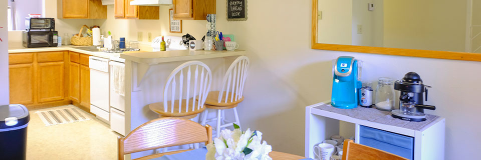 A kitchen and dining room area with a mini-bar and shelves