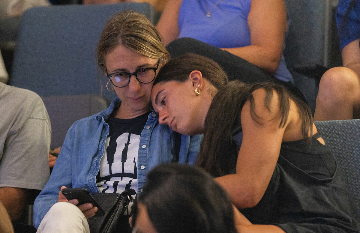 A daughter lays her head on her mom's shoulder on the last day of new student orientation