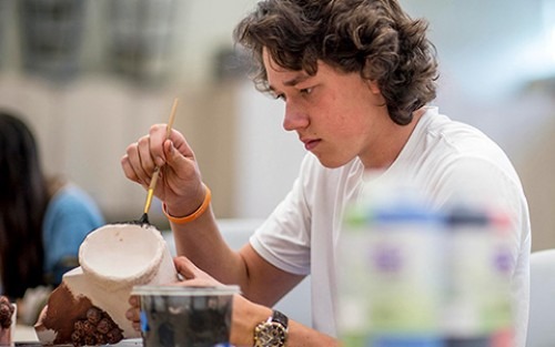 A student paints a ceramics piece