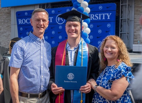 A graduate stands with his parents after Commencement