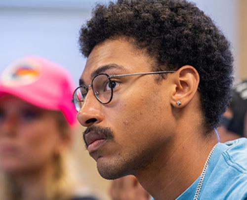 Student with glasses looking seriously at front of classroom