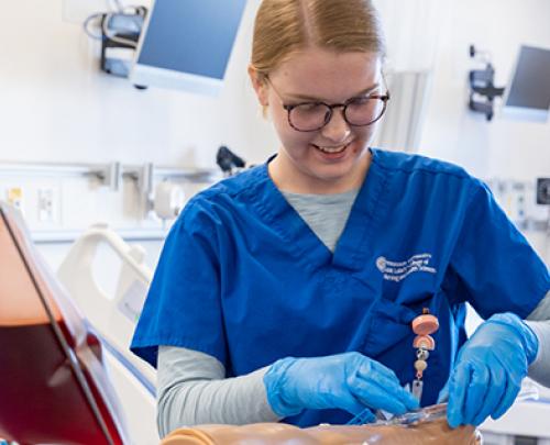 Nursing students practicing procedures on an arm