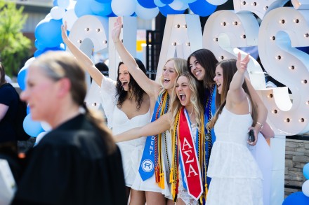 Students cheering and smiling with arms up at graduation