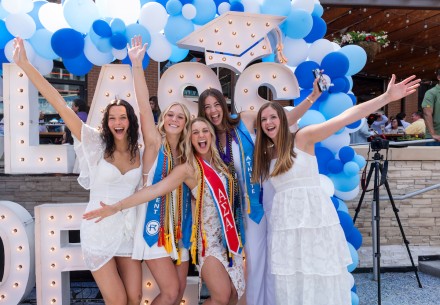 Group of female students at graduation cheering and smiling