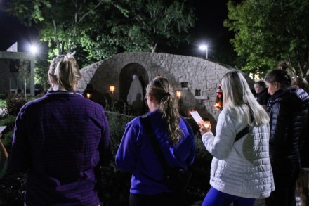 Students standing in prayer around the Mary Grotto on Rockhurst campus