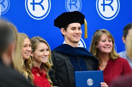 An OTD graduate poses with his family after the hooding ceremony