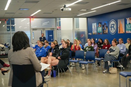 Women athletes listen to a speaker in the MAC Commons room