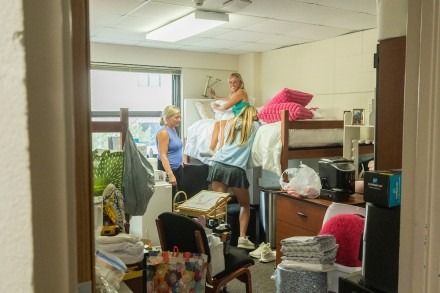 Two girls and a mom sort through belongings during dorm move-in