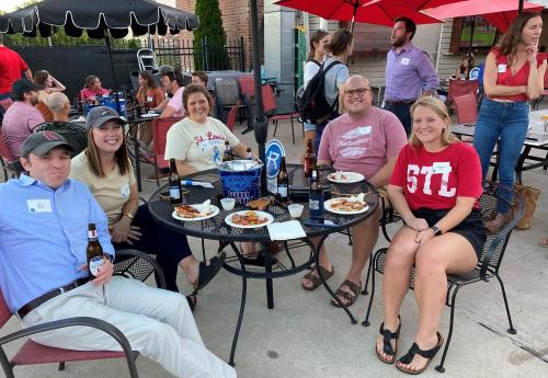 Rockhurst alumni sit around a patio table at a watch party